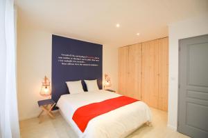 ein Schlafzimmer mit einem Bett mit einer rot-weißen Decke in der Unterkunft La Maison Bleue - En plein cœur d'Arcachon in Arcachon