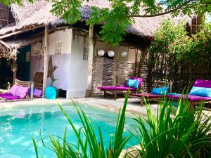 a resort with a pool and chairs in front of it at Zanzistar Lodge in Jambiani