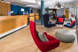 a waiting room with red chairs and a table at Holiday Inn Express Burton on Trent, an IHG Hotel in Burton upon Trent