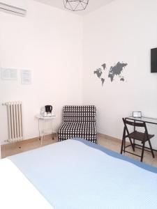 a white bedroom with a bed and a chair at B&B Portarotese in Salerno