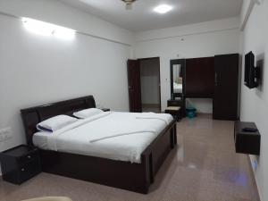 a bedroom with a large bed with white sheets at Hosamane Farm Inn in Sringeri