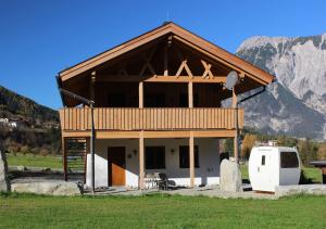 ein Haus auf einem Feld mit einem Berg im Hintergrund in der Unterkunft X-Alp Lodges in Sautens