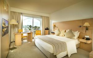 ein Hotelzimmer mit einem großen Bett und einem Schreibtisch in der Unterkunft Occidental Sfax Centre in Sfax