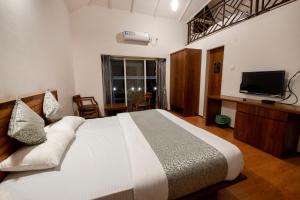 a bedroom with a large bed and a television at Kabila Agro Tourism in Mahabaleshwar