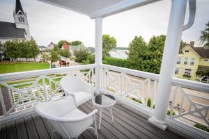 a balcony with white chairs and a view of the water at Harbour View Inn in Mackinac Island