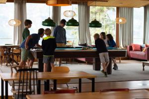 een groep kinderen die rond een pooltafel staan bij Hôtel Plein Ciel in Champéry