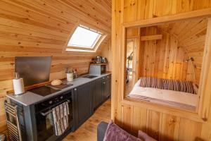a kitchen in a log cabin with a stove at Lawers Luxury Glamping Pet Friendly Pod at Pitilie Pods in Aberfeldy