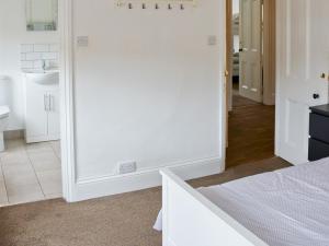 a white bedroom with a bed and a bathroom at Corner House apartment in Worthing