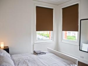 a white bedroom with two windows and a bed at Corner House apartment in Worthing