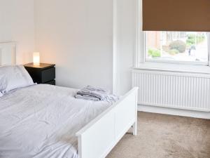 a white bedroom with a bed and a window at Corner House apartment in Worthing