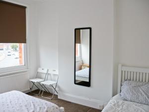 ein Schlafzimmer mit einem Spiegel, einem Bett und einem Fenster in der Unterkunft Corner House apartment in Worthing + 3 Fotos