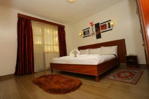 ein Schlafzimmer mit einem großen Bett und einem Teppich in der Unterkunft Merril Hotel in Eldoret