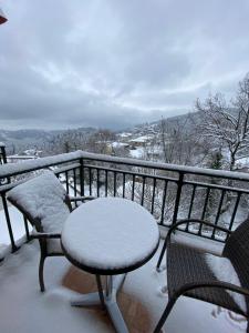 balcón con mesa y sillas cubiertas de nieve en Nefeles, en Neochori