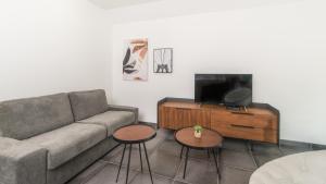 a living room with a couch and two tables and a tv at Villa Sunshine avec Jacuzzi Privatif in Sarlat-la-Canéda