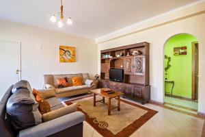een woonkamer met een bank en een tv bij T2 Anastácio com vista Jardim in Olhos de Água