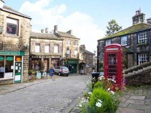eine altmodische Straße mit einer roten Telefonzelle und Gebäuden in der Unterkunft Owl Cottage in Keighley