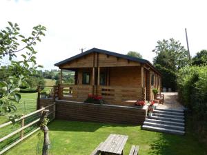 a small wooden cabin in a field with a fence at Pound Farm Holidays - Orchard Lodge in Cullompton