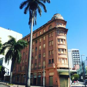a tall brick building with a palm tree in front of it at Sul América Palace Hotel in Belo Horizonte