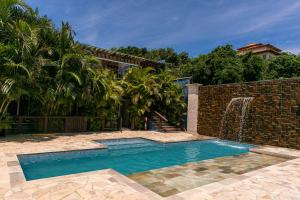 uma piscina ao lado de uma parede de tijolos com uma cascata em Pousada La Dolce Vita em Búzios