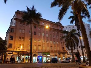 een groot gebouw met palmbomen voor een straat bij Sul América Palace Hotel in Belo Horizonte