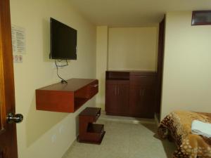 1 dormitorio con 1 cama y TV en la pared en Hotel Suyusama, en Ipiales