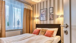 a bed with two pillows and a window in a room at Apartament Francuski - 5D Apartamenty in Świeradów-Zdrój