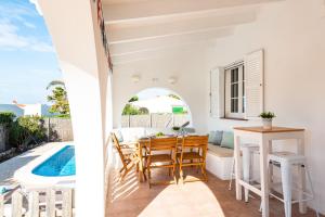 a dining room with a table and chairs next to a pool at Casa Blanca - villa con piscina a 30m del mar-Binibeca in Sant Lluis