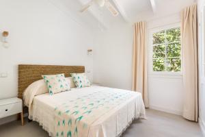 a white bedroom with a bed and a window at Casa Blanca - villa con piscina a 30m del mar-Binibeca in Sant Lluis +18 photos