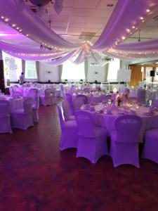 una sala banchetti con tavoli e sedie viola e soffitti di Gasthaus Gonnermann a Sontra