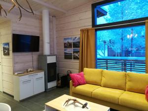 a living room with a yellow couch and a large window at Lomatärppi in Utsjoki