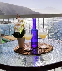 una mesa con dos copas de vino y una botella azul en Tenerife Anahata Relax Vv, en Tacoronte