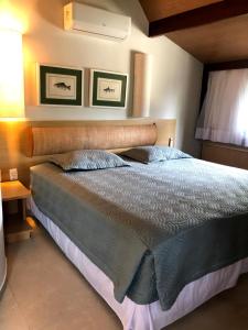 - une chambre avec un grand lit et une tête de lit en bois dans l'établissement Bangalô Luxo Beach Class Resort Muro Alto, à Porto de Galinhas