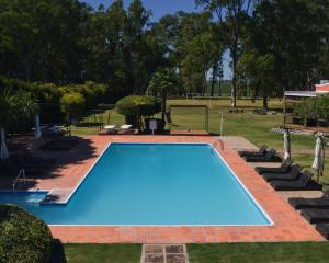 une grande piscine bleue dans une cour dans l'établissement Casa del Sol Hotel & Restaurante, à Colonia del Sacramento