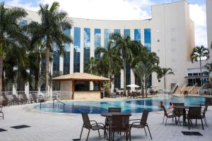 a pool with tables and chairs in front of a building at Barretos Park Hotel in Barretos