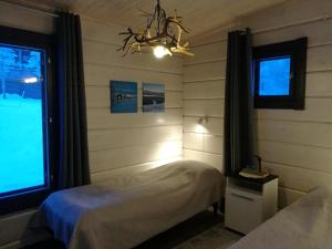 a bedroom with two beds and a window and a chandelier at Lomatärppi in Utsjoki