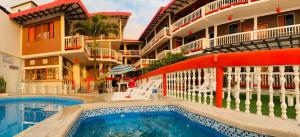 a hotel with a swimming pool in front of a building at Charo´s Hostal in Montañita