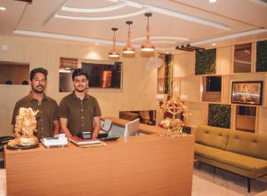 two men standing at a counter in a room at Hotel Mount View Comforts in Tirupati