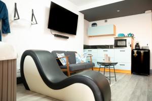 a living room with a couch and a tv on a wall at Au Charm'Sablais in Les Sables-d'Olonne