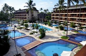 an aerial view of a resort with pools and umbrellas at Nannai Beira Mar, Flat Duplex em Muro Alto - Porto de Galinhas in Porto De Galinhas