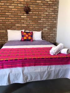 a large bed in a room with a brick wall at Pousada Pico Da Vila in Vale do Capao