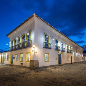 een groot wit gebouw met ramen en balkons 's nachts bij Sandi Hotel in Paraty