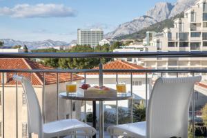 a table and two chairs on a balcony with drinks at Beach Spot Apartments in Makarska