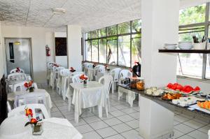 Natal Palace Hotel في ناتال: غرفة طعام مع طاولات بيضاء وكراسي بيضاء