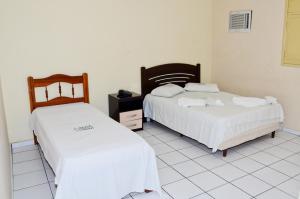 two beds in a room with white tiled floors at Natal Palace Hotel in Natal