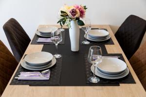 a table with plates and glasses and a vase with flowers at Apart Compliment in Podgorica