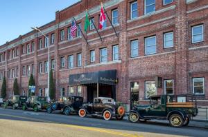 a row of antique cars parked in front of a brick building at MarQueen Hotel in Seattle