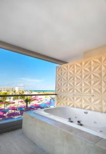 a large bathroom with a tub and a large window at Planet Hollywood Adult Scene Cancun, An Autograph Collection All- Inclusive Resort - Adults Only in Canc&uacute;n