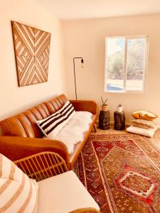 uma sala de estar com um sofá de couro e uma janela em Casa Agave: Comfy Joshua Tree Cottage With Free Breakfast Bar em Joshua Tree