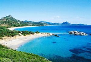 een strand met blauw water en bergen op de achtergrond bij B&B Nel Giardino In Fiore in Castiadas