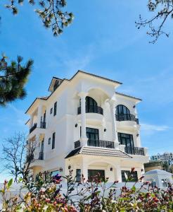 大叻的住宿－Bạch Trà Villa，带阳台和树木的白色建筑